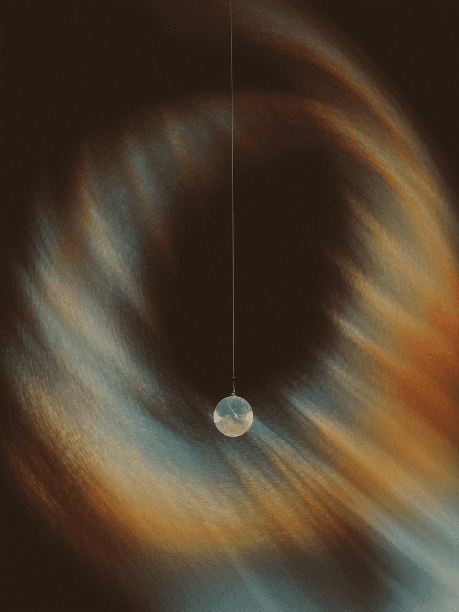 A glowing orb centered in swirling dark cosmic rainbow light.